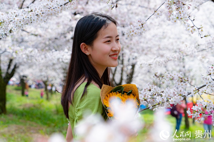 游客站在花叢中與櫻花合影留念。人民網(wǎng) 陽茜攝