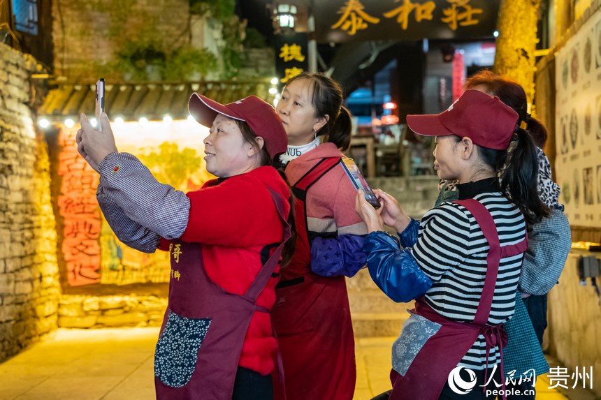 古鎮(zhèn)里的商販站在街道旁拍攝古鎮(zhèn)新貌。人民網(wǎng) 陽茜攝