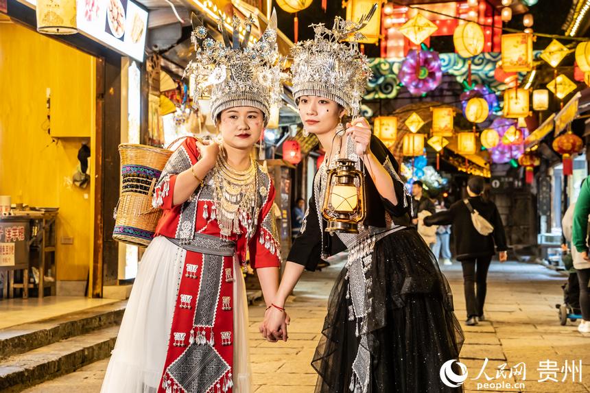 游客身著民族服飾站在古鎮(zhèn)街道上合影。人民網(wǎng) 陽(yáng)茜攝