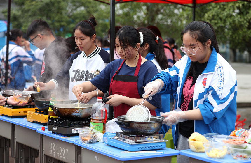 高三年級學生在“校園美食節(jié)”上烹飪美食。黃曉海攝
