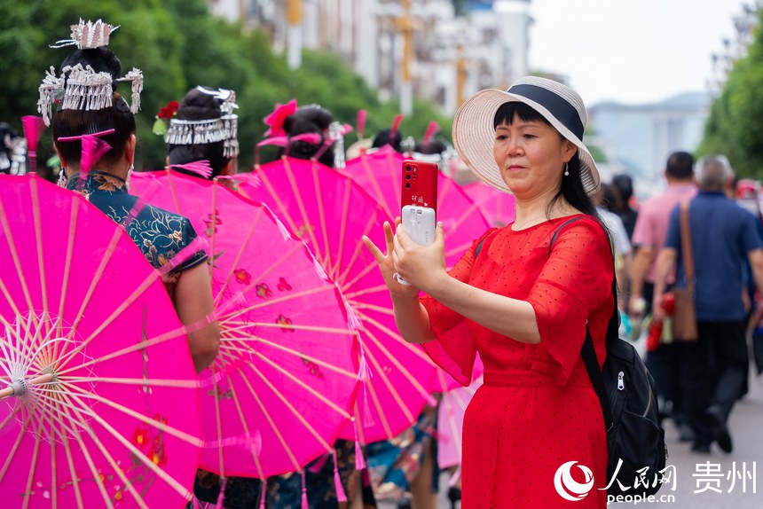 圍觀的群眾用手機(jī)拍攝少數(shù)民族同胞巡游。人民網(wǎng)記者 涂敏攝
