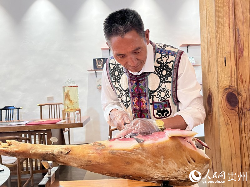 王福生正在切鮮火腿給游客品嘗。人民網(wǎng) 陳潔泉攝