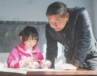 李明軍（右）在輔導(dǎo)學(xué)生做作業(yè)。