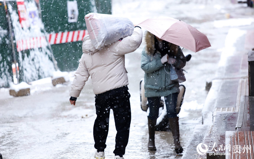 行人扛著袋子在雪中行走。人民網(wǎng) 顧蘭云攝