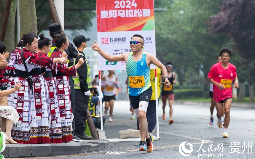 參賽選手與身著少數(shù)民族服飾的觀眾打招呼。人民網(wǎng)記者 高華攝