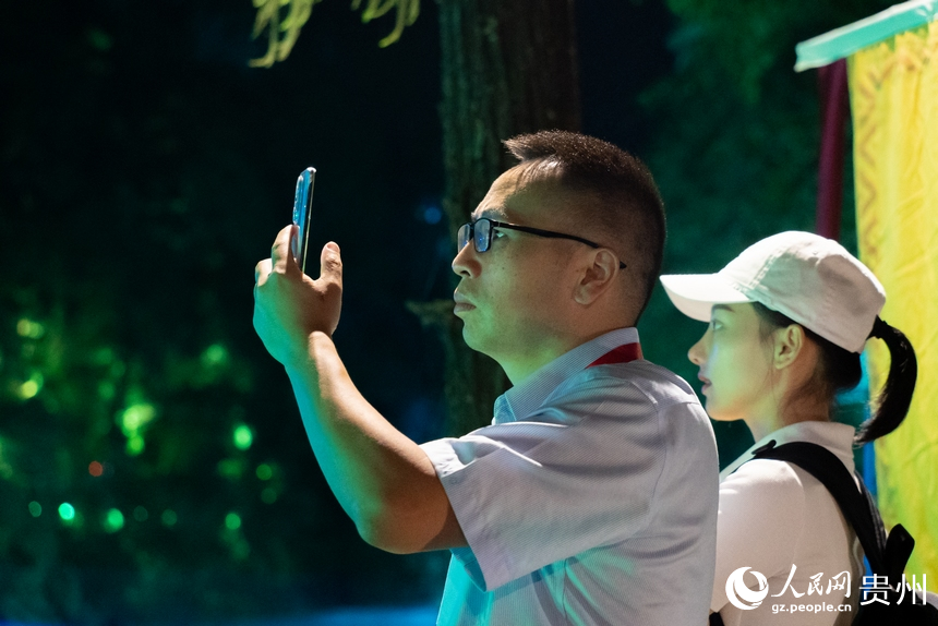 游客在夜間黃果樹瀑布前打卡拍照。人民網(wǎng)記者 涂敏攝