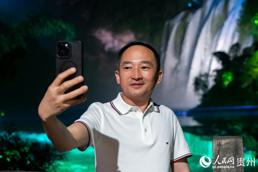 游客在夜間黃果樹瀑布前打卡拍照。人民網(wǎng)記者 涂敏攝