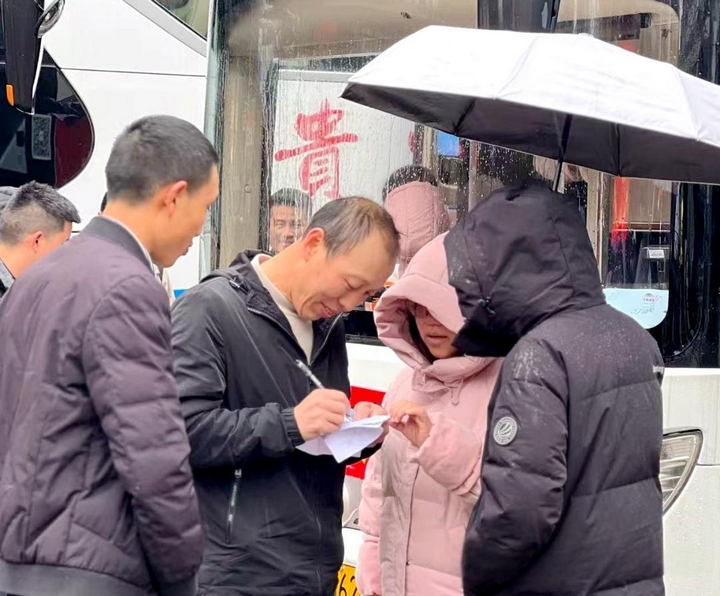 活動(dòng)現(xiàn)場，工作人員確認(rèn)務(wù)工群眾乘車名單。習(xí)水縣融媒體中心供圖）.jpg