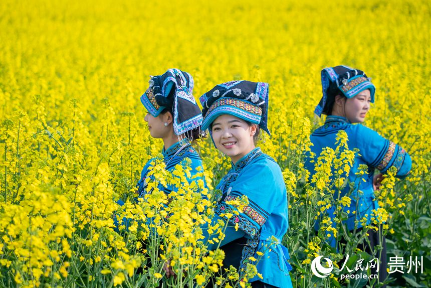 身著少數(shù)民族服飾的女孩在花田中拍照。人民網記者 涂敏攝