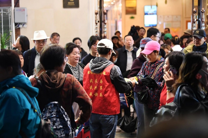 4月24日，志愿者為花果園旅游大巴集散地游客免費發(fā)放雨衣。