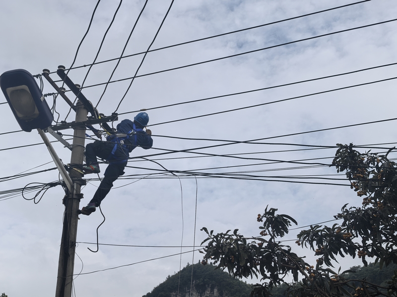 工作人員在電桿上進行下戶線的搭火工作。